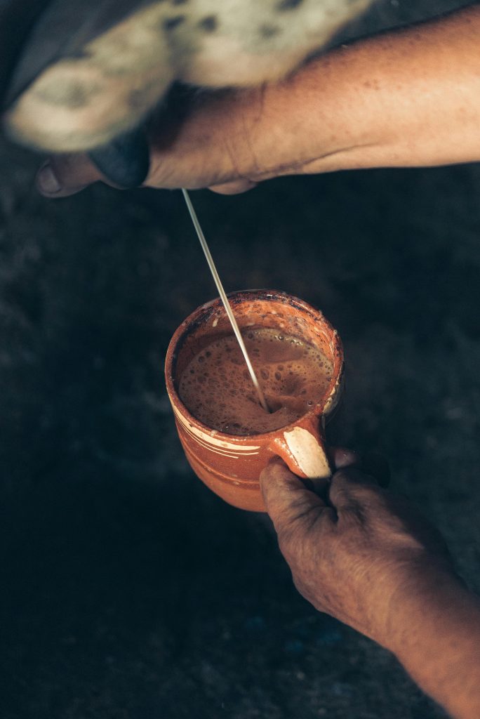 Close-up of hands milking a cow into a ceramic mug on a farm.